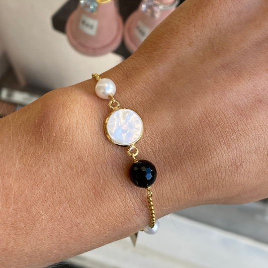Bruno onyx, mother of pearl, and pearl bracelet with mixed gemstone beads on a jewelry display.