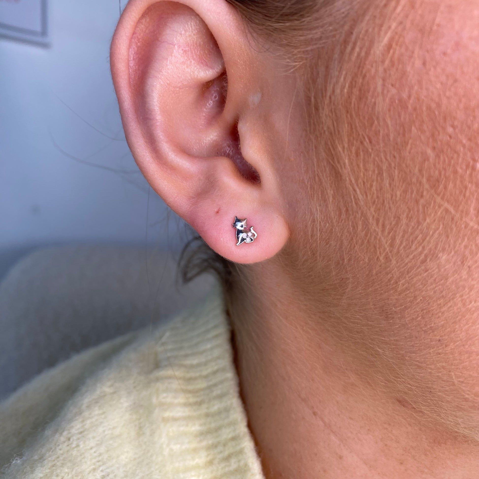 Silver CZ cat silhouette kid's stud earrings by Comero featuring shiny, adorable feline-shaped jewelry for children.