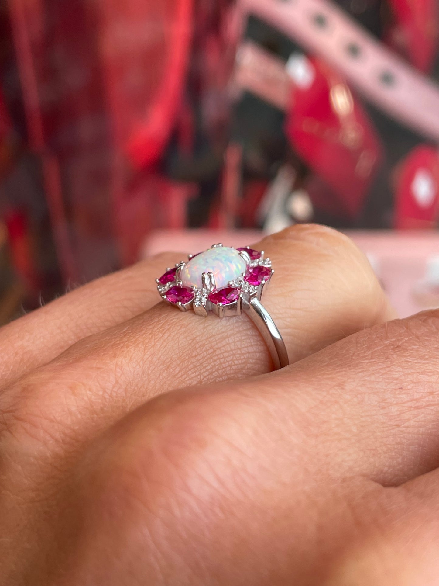 Silver oval Diana cluster ring with opal and ruby red accents by Comero, featuring a detailed floral design and polished finish.