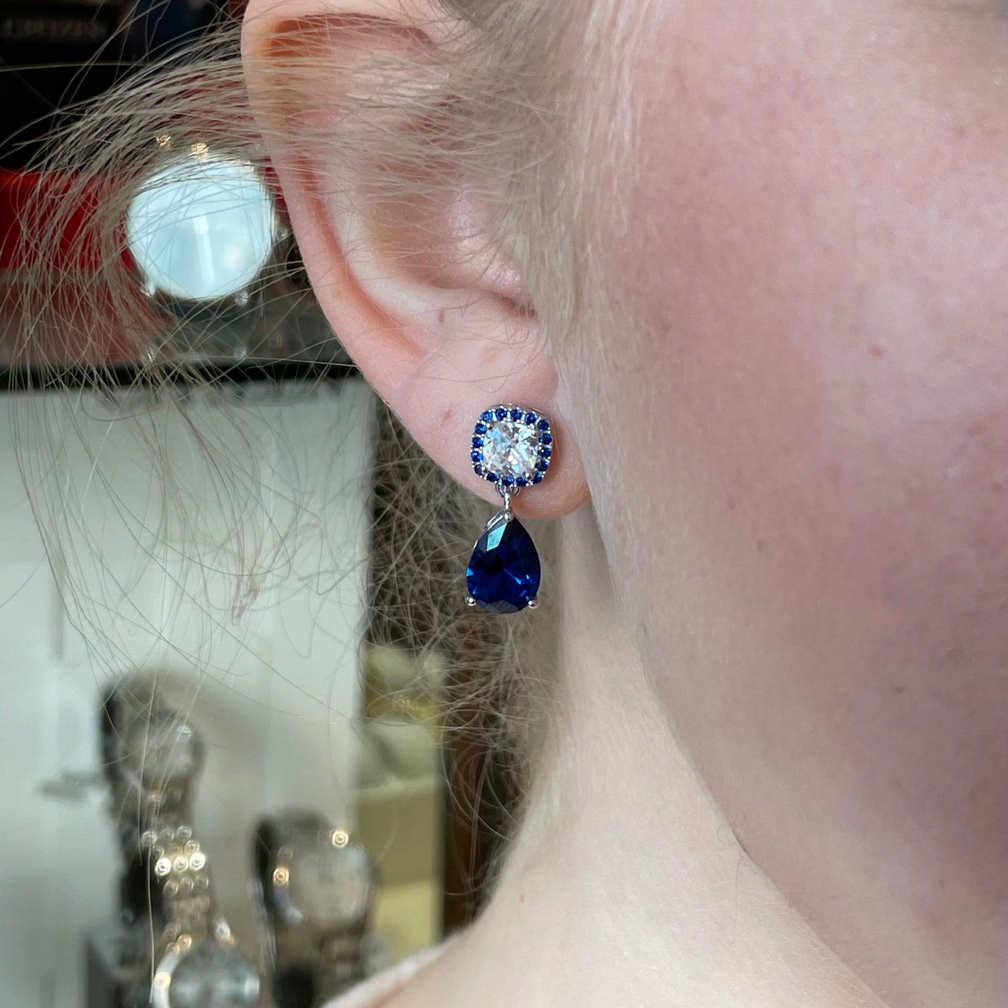 Silver Sapphire Blue Pear CZ drop earrings by Comero featuring dangling teardrop-shaped blue cubic zirconia stones.