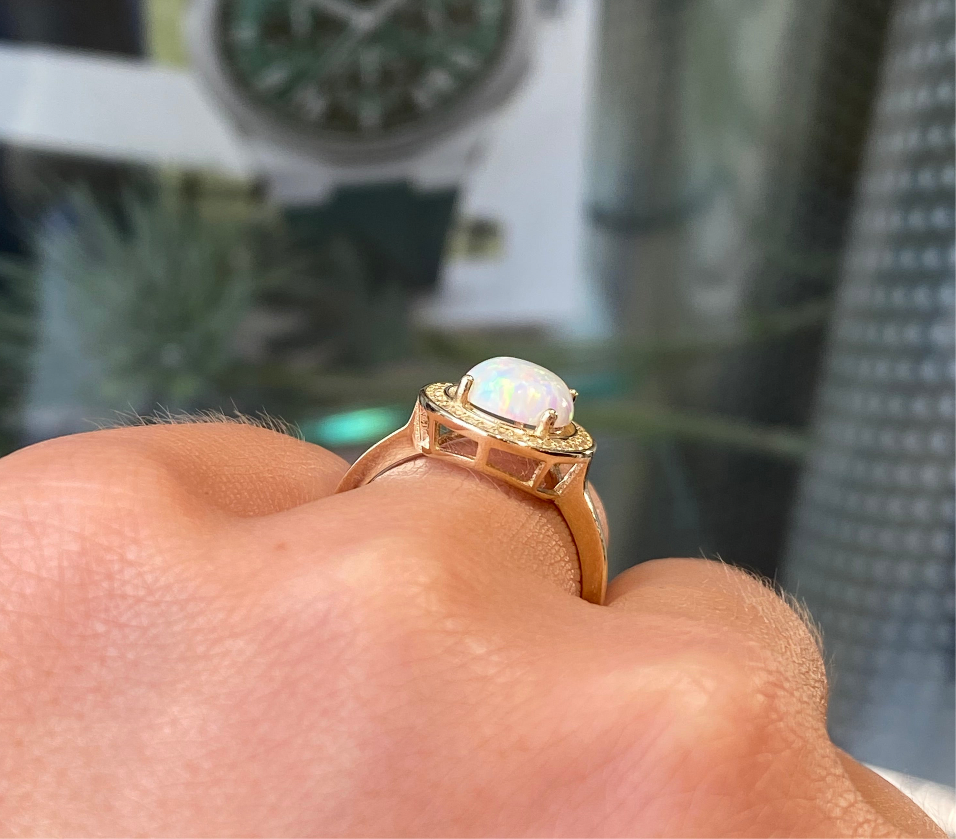 9ct gold oval opalique and cubic zirconia ring showcasing a elegant design with a gold band and sparkling stones.