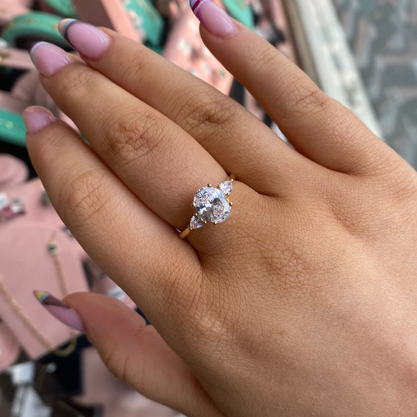 9ct gold CZ trilogy ring with oval center gemstone by PJD, showcasing a polished gold band and sparkling cubic zirconia stones.