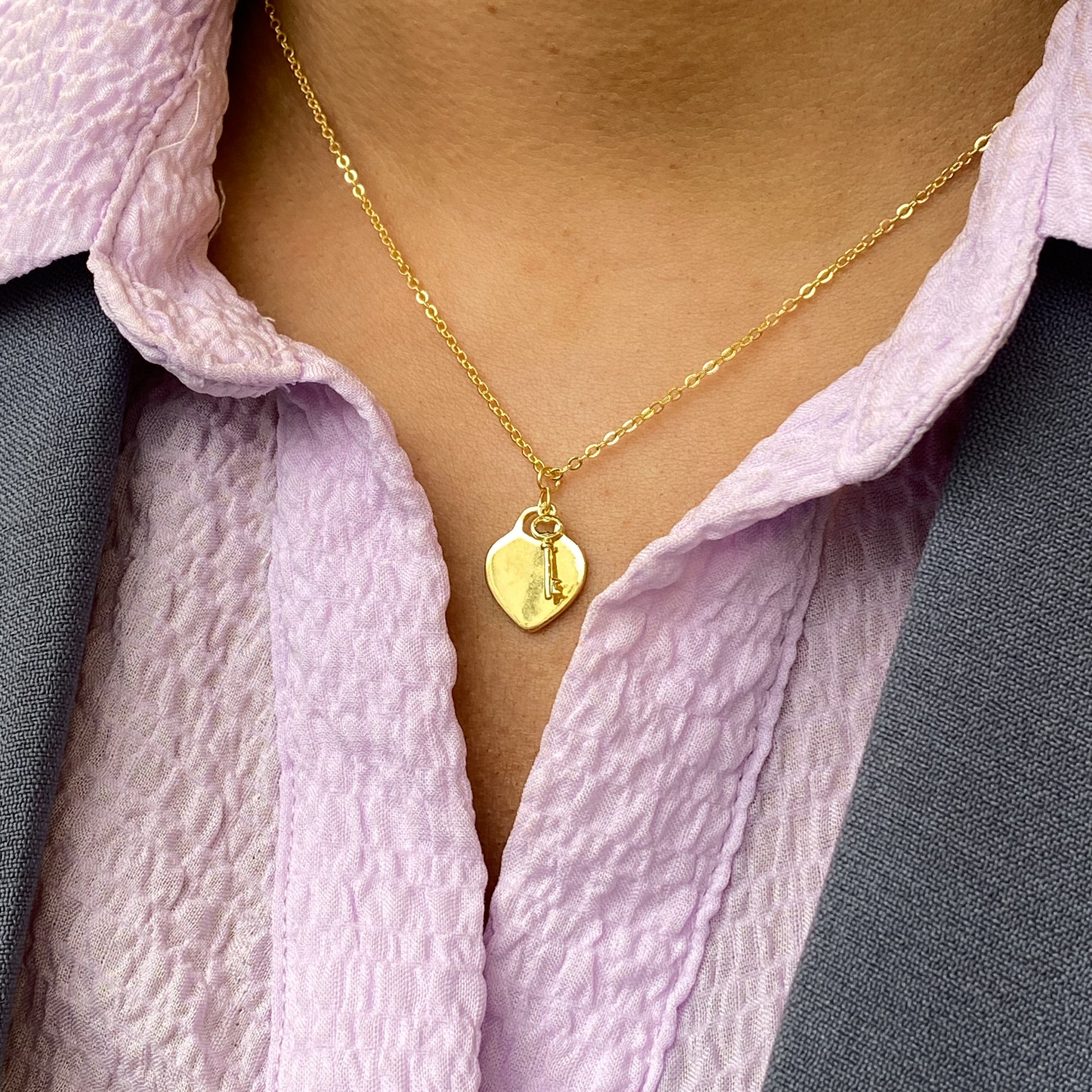 Sunshine Key To My Heart disc necklace by Comero featuring a gold-tone chain and heart-shaped pendant with sun and key design elements.