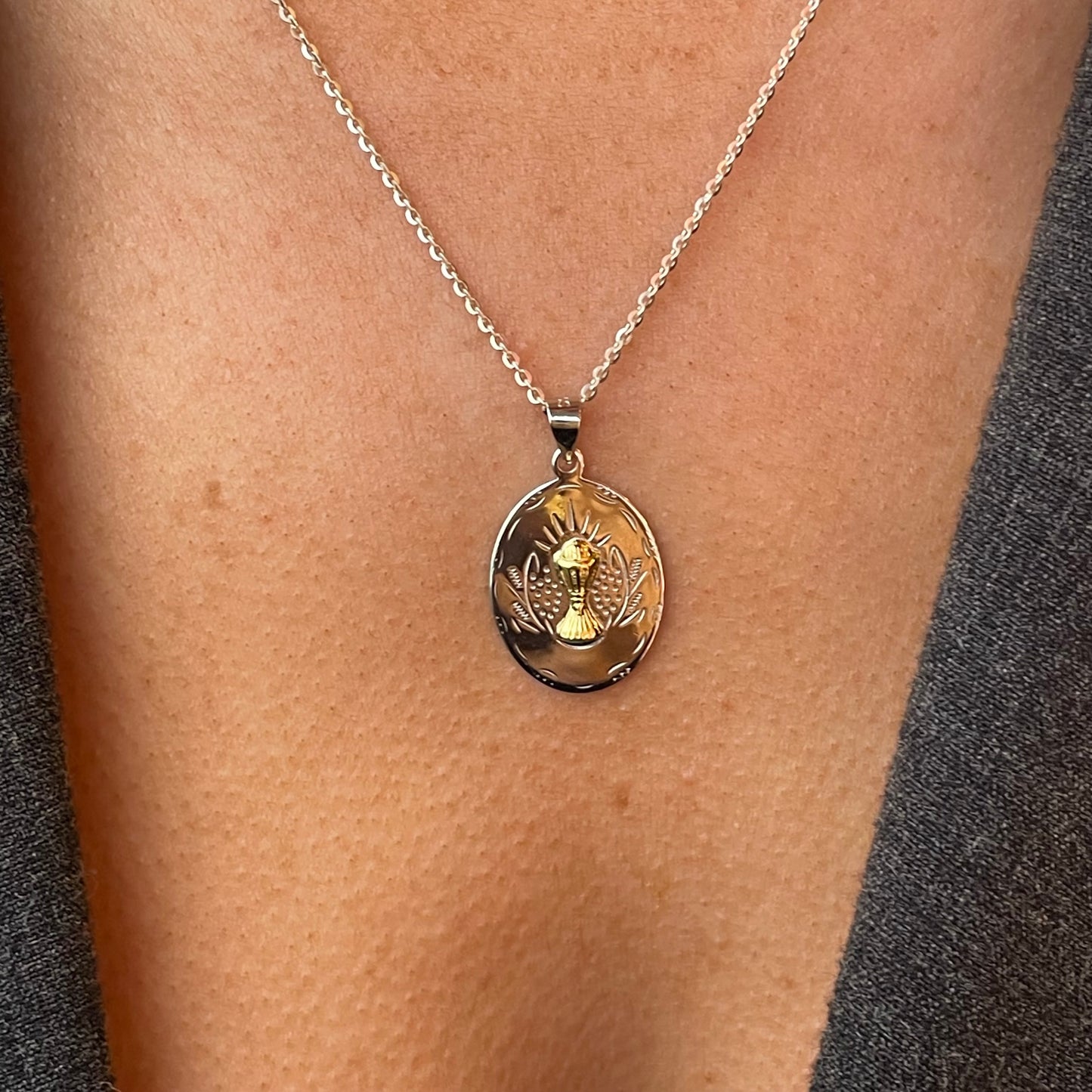 Silver two-tone oval communion medal necklace by Comero, 18-inch chain with detailed religious pendant.