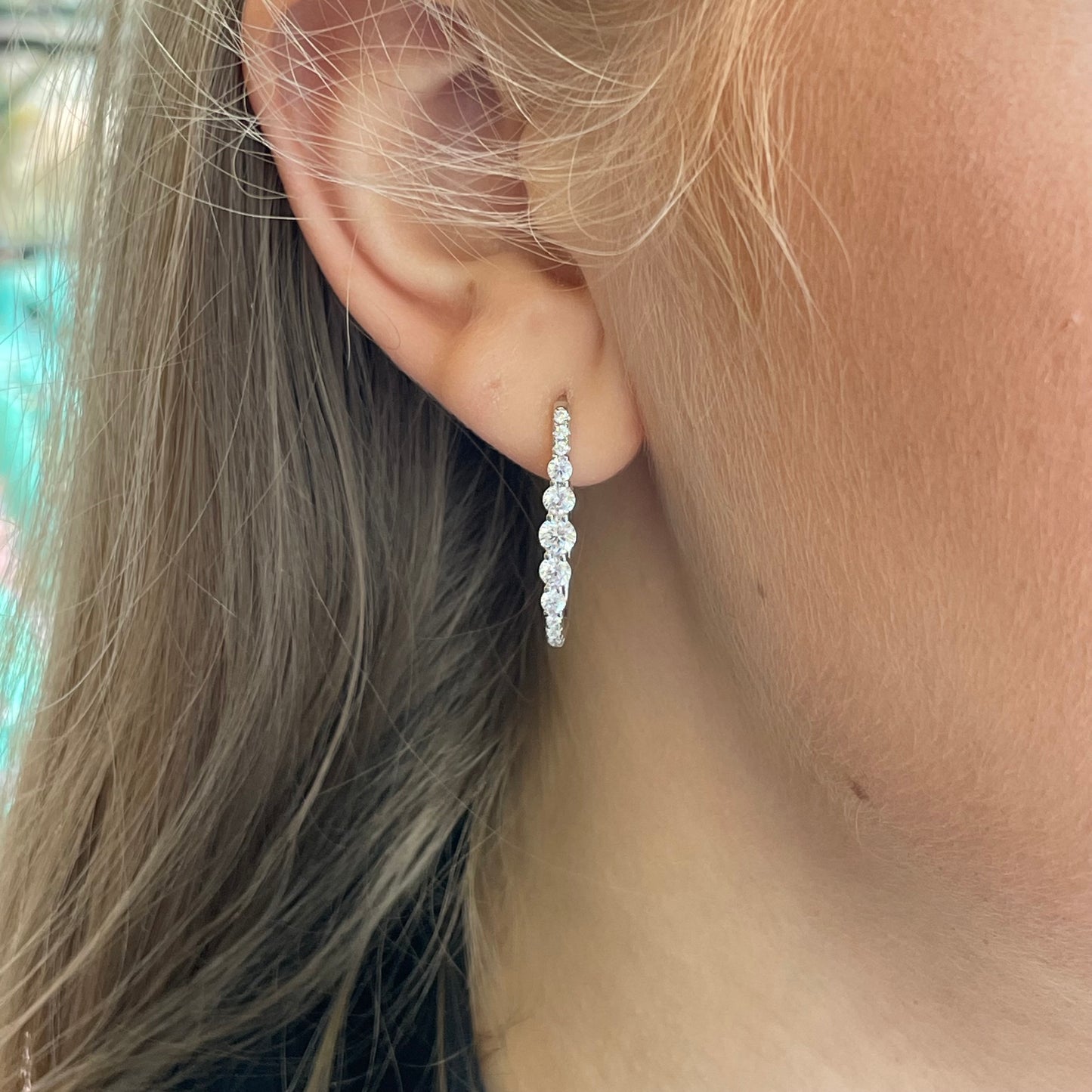 Silver elongated CZ huggie hoop earrings by Comero, featuring sparkling cubic zirconia stones and sleek, modern hoop design.