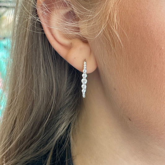 Silver elongated CZ huggie hoop earrings by Comero, featuring sparkling cubic zirconia stones and sleek, modern hoop design.
