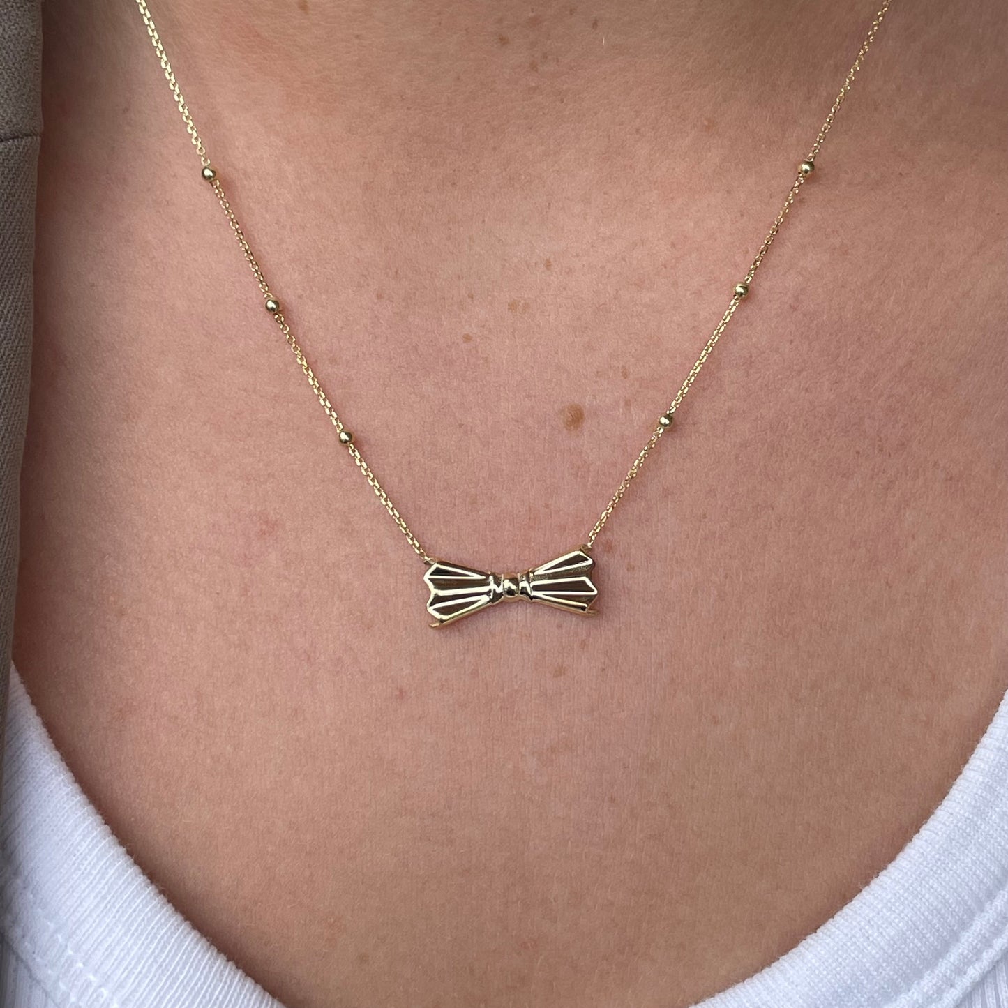 9ct gold bow and bead necklace with delicate design, showcasing a stylish gold jewelry piece by NJO.