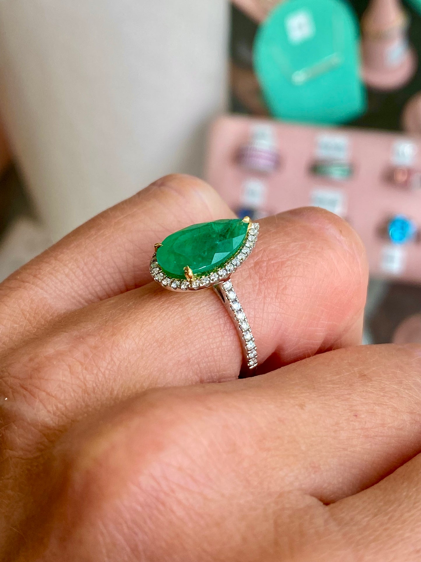 Herbert platinum emerald and diamond pear-shaped ring featuring a central emerald gemstone surrounded by sparkling diamonds.