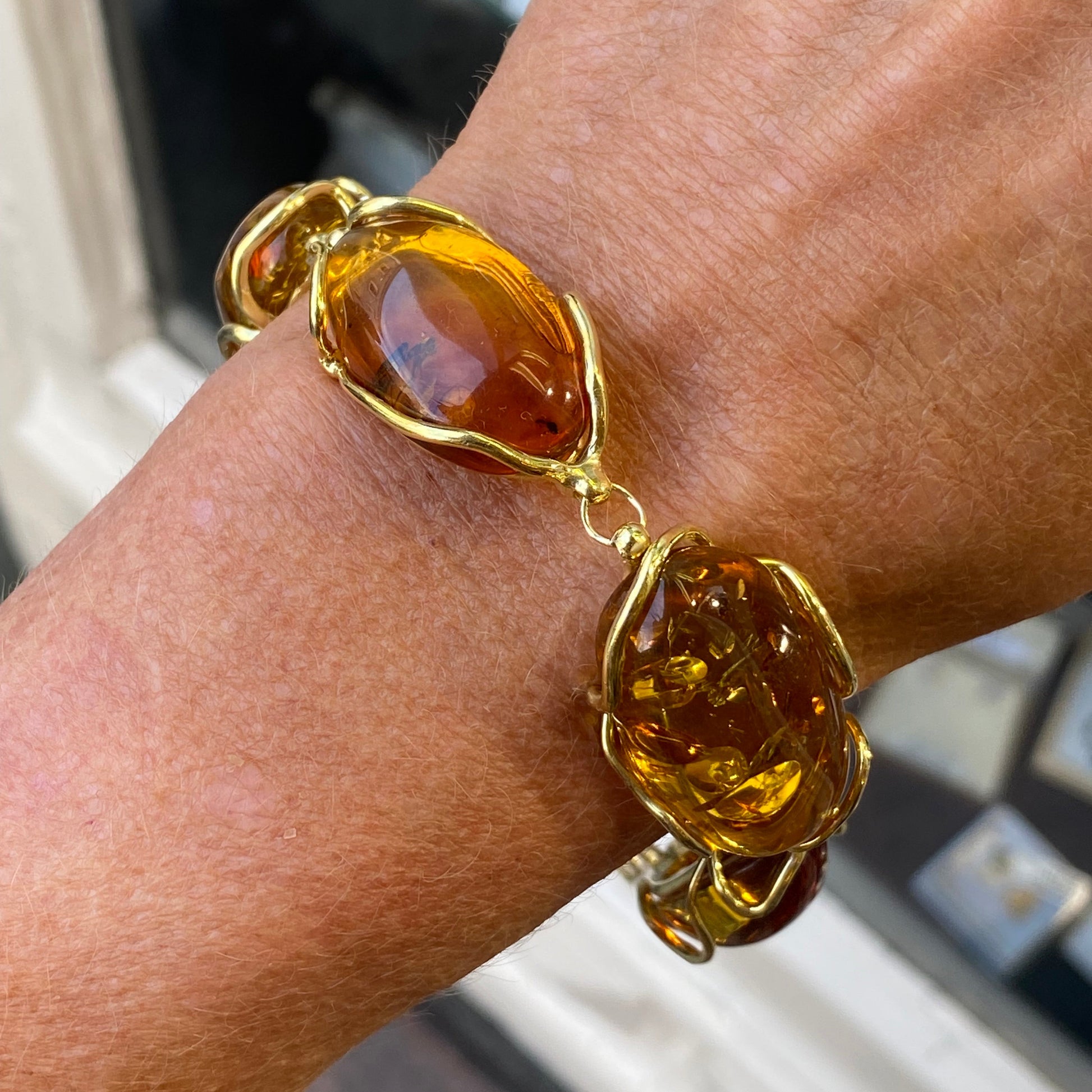 Gold bracelet with amber stones on a wrist.