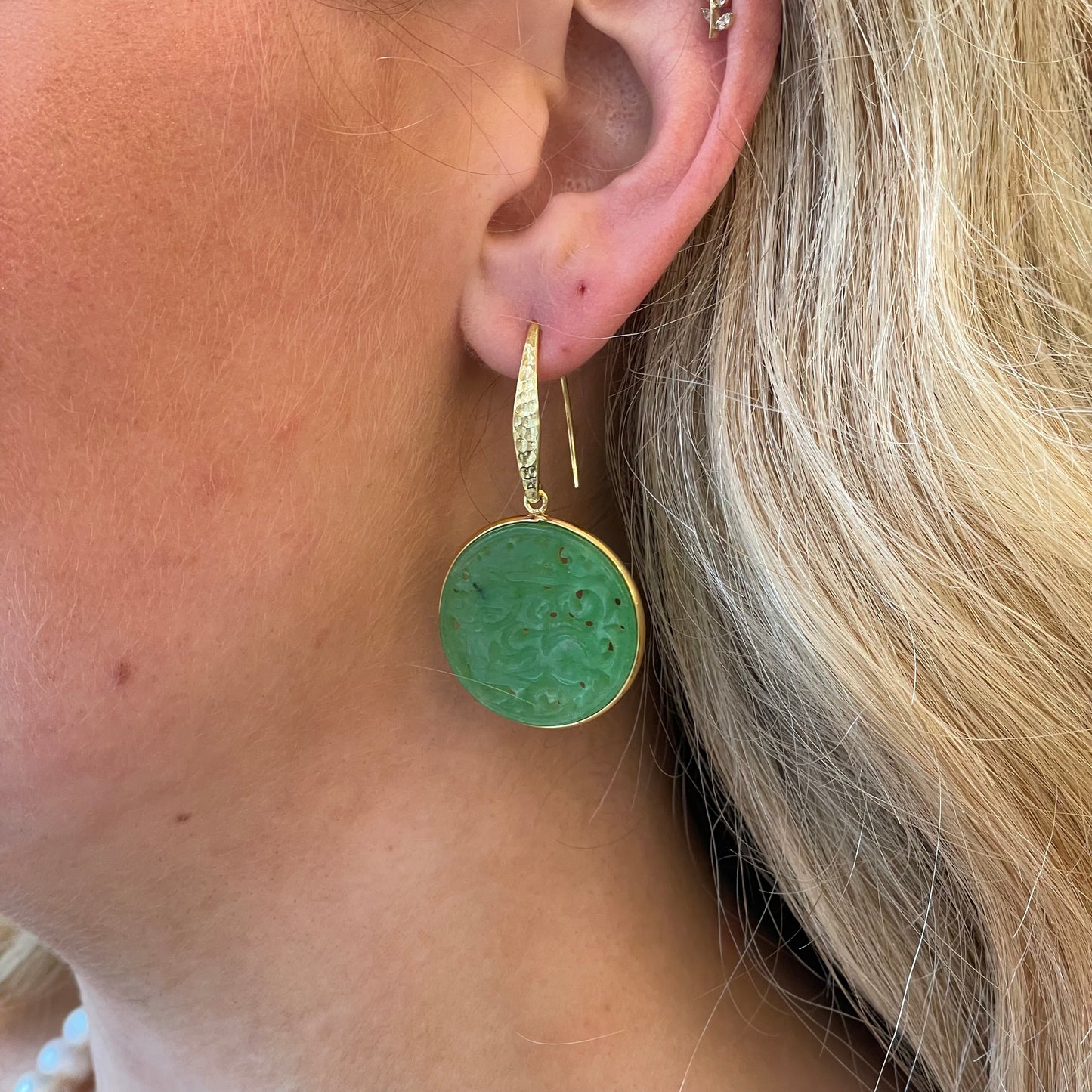 Bruno carved jade round hook drop earrings featuring smooth, polished jade with intricate carvings on a silver hook.