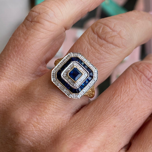 9ct gold sapphire and diamond ring by Luke Stockley, featuring a central sapphire gemstone surrounded by sparkling diamonds.