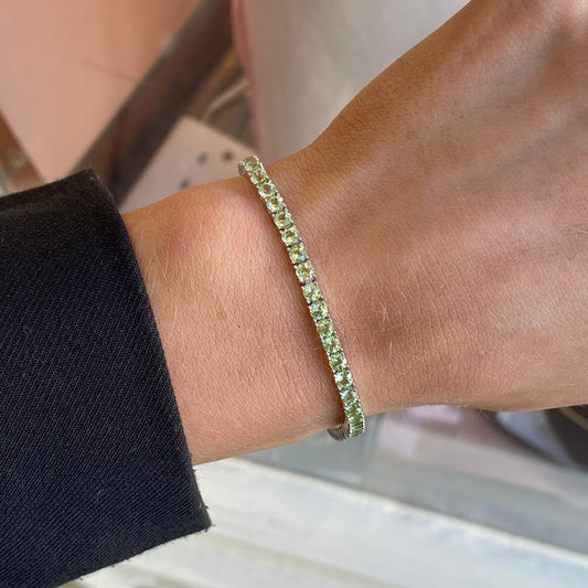 Silver Claw Set Peridot Tennis Bracelet by Insignia featuring silver links with peridot gemstone accents.