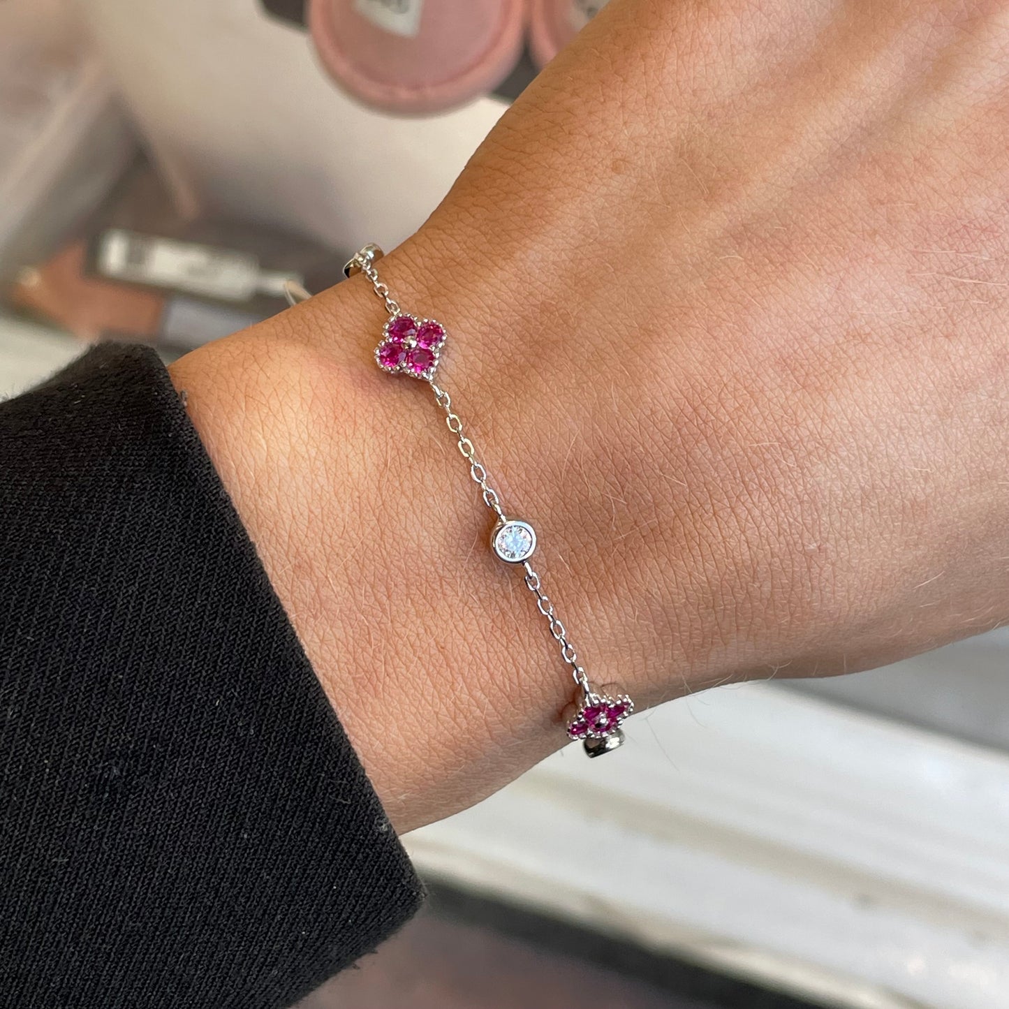 Silver CZ quatrefoil bracelet with ruby red accents from Insignia, featuring intricate design and sparkling gemstone details.