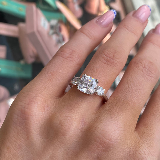 Silver Cushion Trilogy CZ ring by THC featuring a three-stone design with sparkling cubic zirconia and a polished silver band.