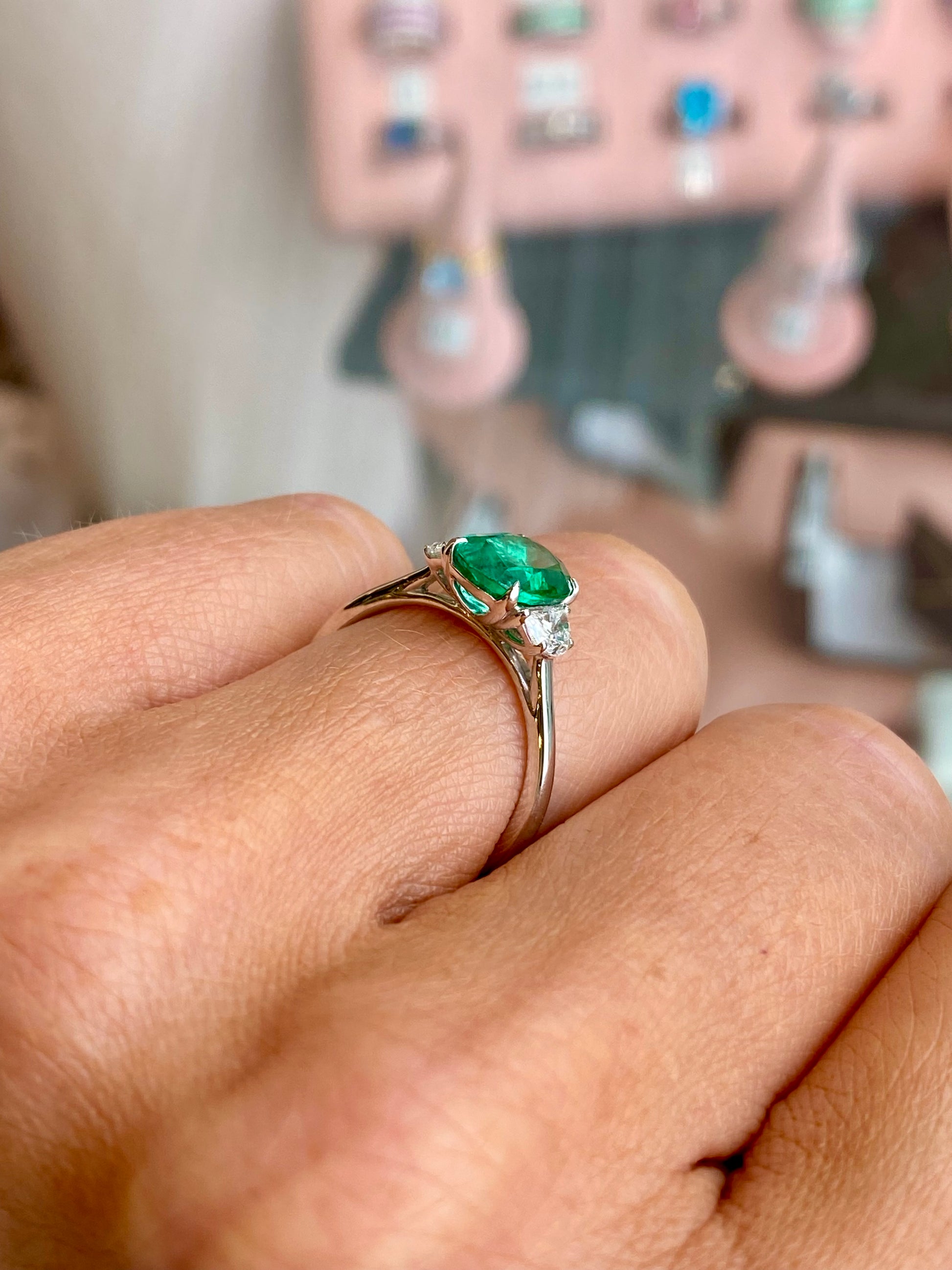 Herbert platinum emerald and diamond ring showcasing a central emerald gemstone surrounded by sparkling diamonds.