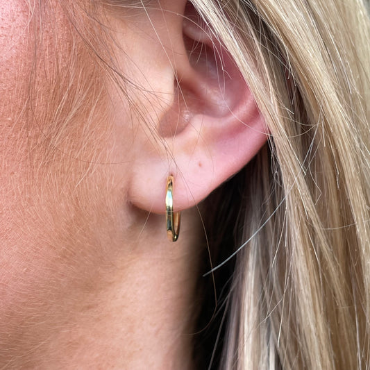 Sunshine Simple Huggie Hoop Earrings by Comero with smooth gold-tone hoops on a white background
