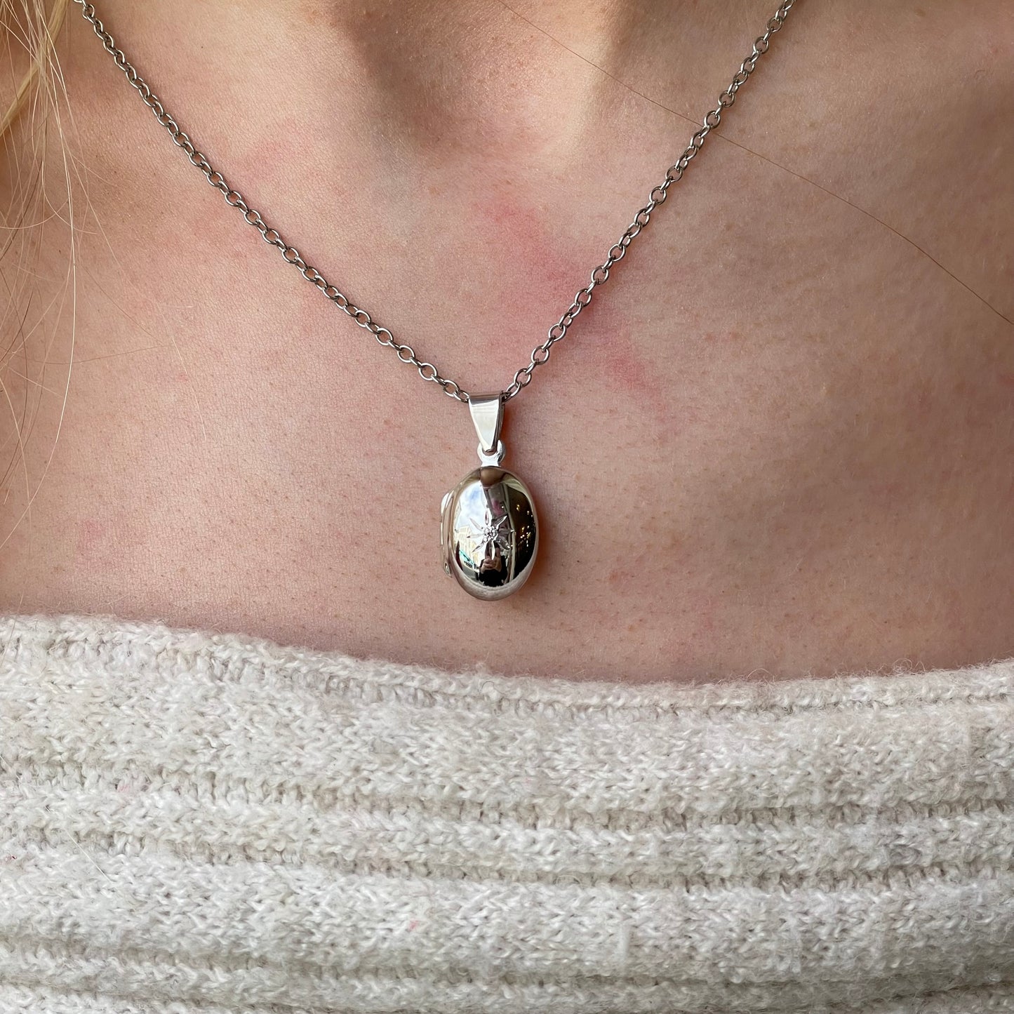 Silver CZ oval locket necklace with chain from Insignia, featuring a polished pendant with sparkling cubic zirconia accents.