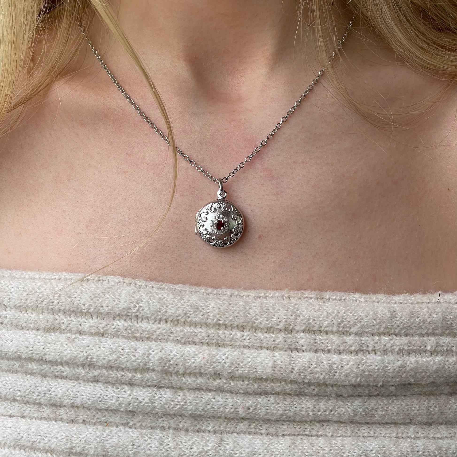 Silver round garnet and CZ embossed locket necklace with chain, featuring detailed design and elegant craftsmanship.