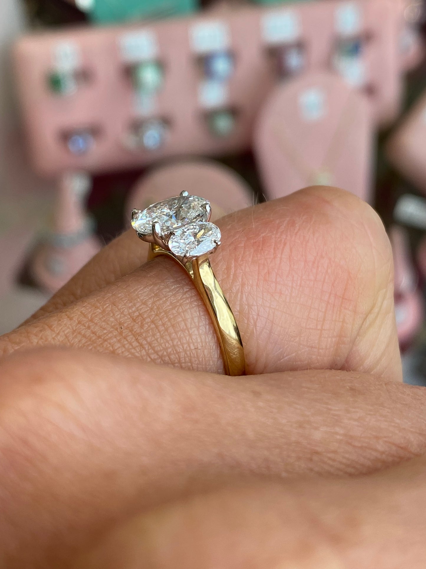 18ct gold oval trilogy engagement ring by TCA featuring a lab-certified 2.40ct central gemstone and side stones.