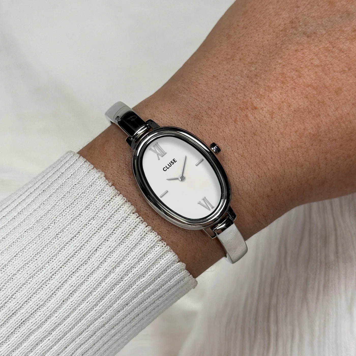 Silver CLUSE L'Ovale watch with a sleek oval face and minimalistic design, featuring a silver strap and elegant details.
