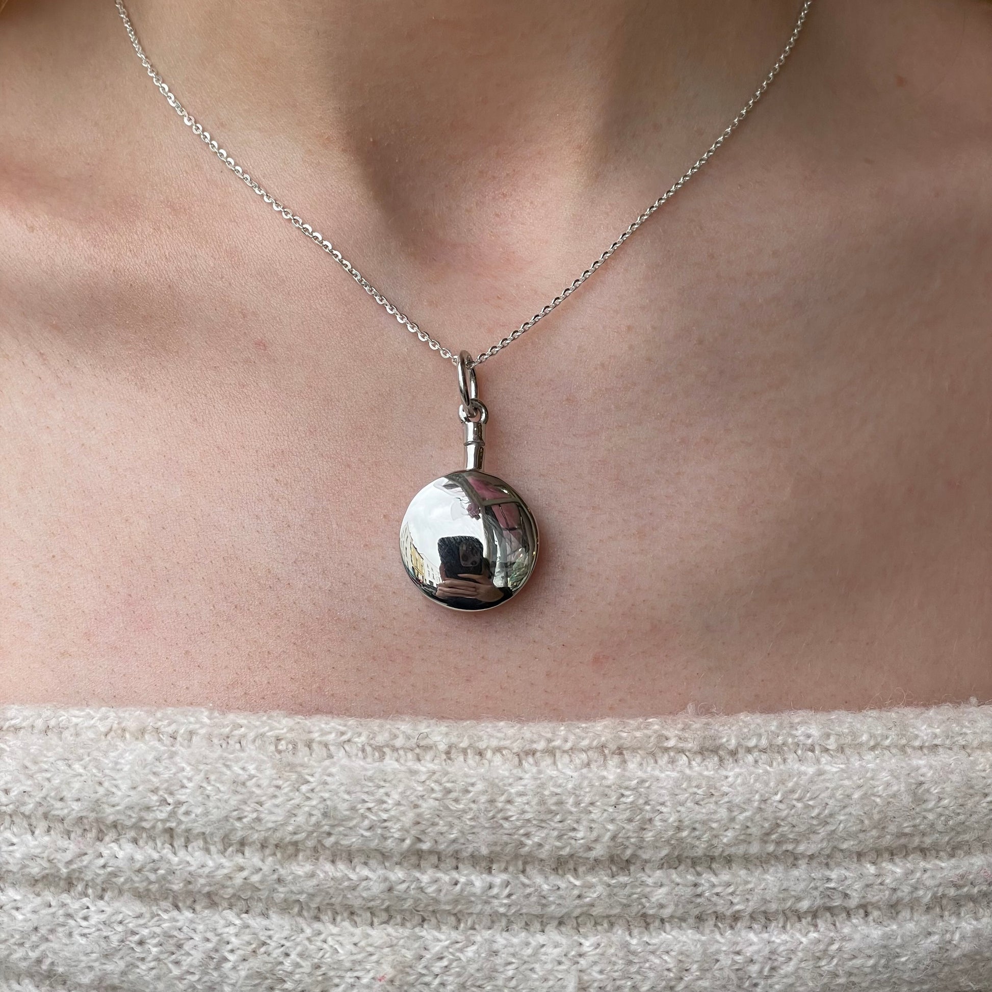 Silver round ash locket necklace by Insignia featuring a polished circular pendant on a delicate chain.