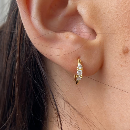 Comero Sunshine Trilogy CZ Huggie Earrings featuring sparkling cubic zirconia stones in a gold-tone hoop design.
