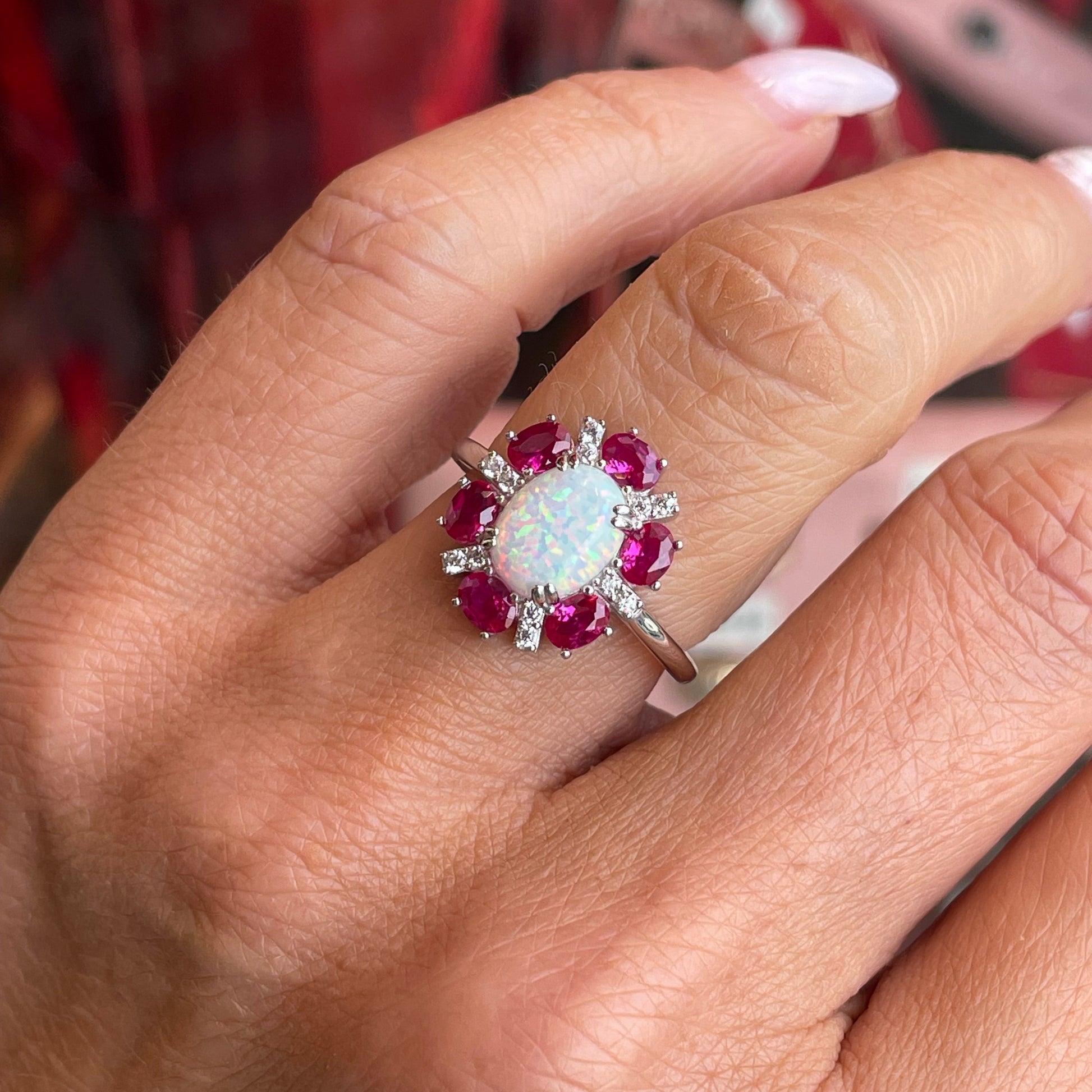 Silver oval Diana cluster ring featuring opal and ruby red accents by Comero, showcasing intricate design and vibrant gemstones.