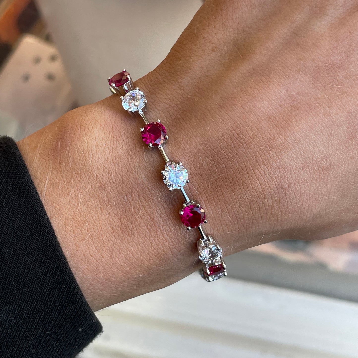 Silver CZ tennis bracelet by Insignia featuring ruby red gemstones and a sleek, elegant design.