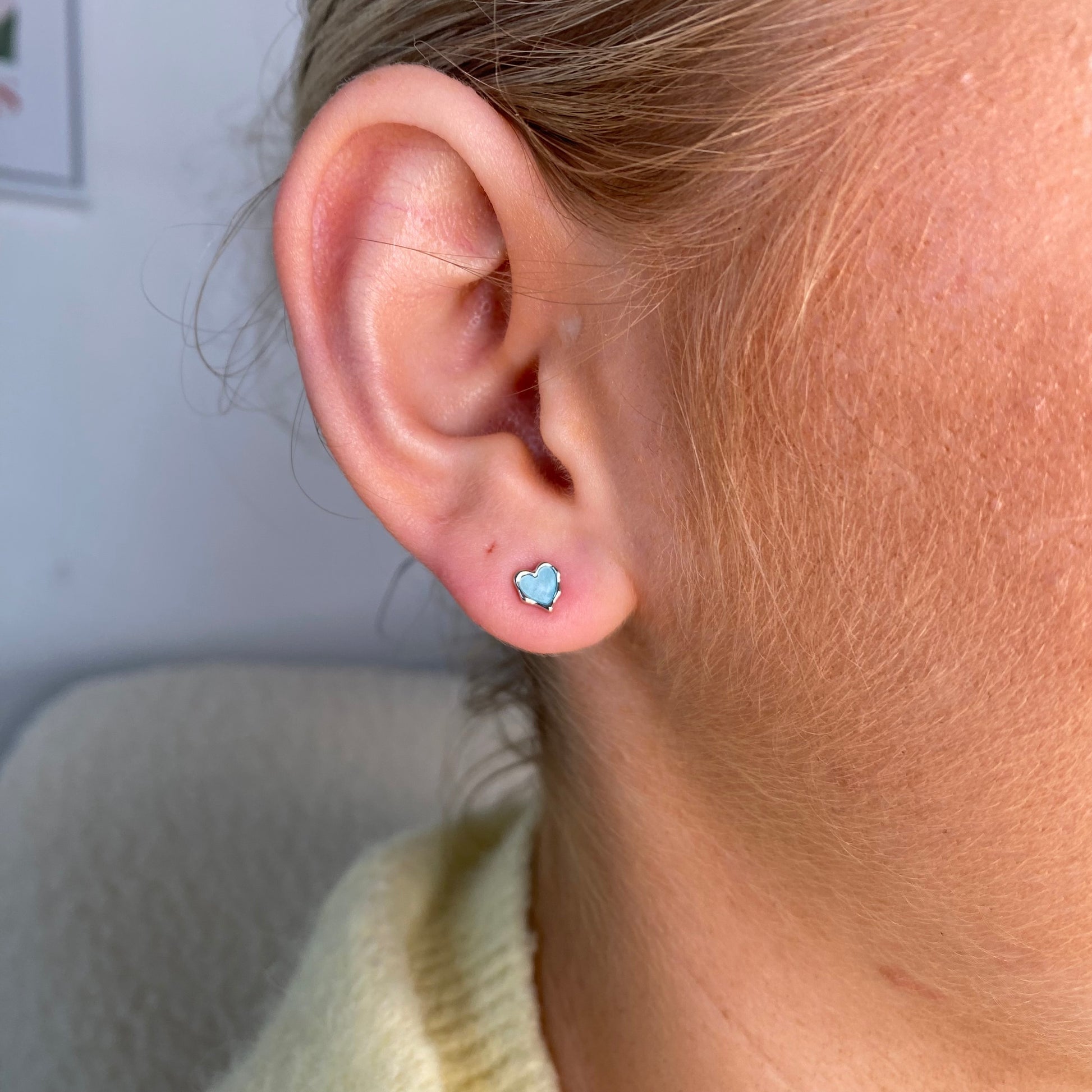Silver enamel heart stud earrings for kids by Comero featuring blue heart-shaped designs on shiny silver studs.
