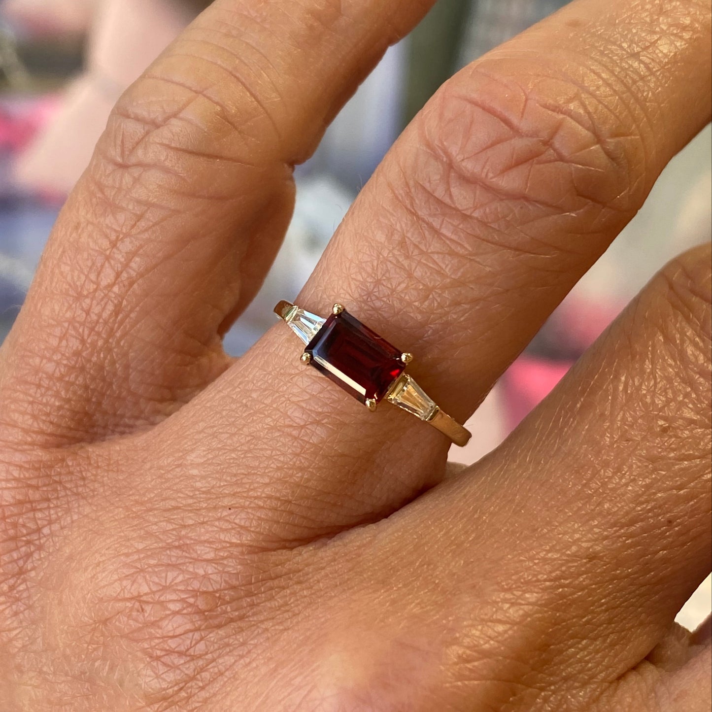 Insignia 9ct gold east-west ring featuring a garnet center stone with CZ accents on a white background.