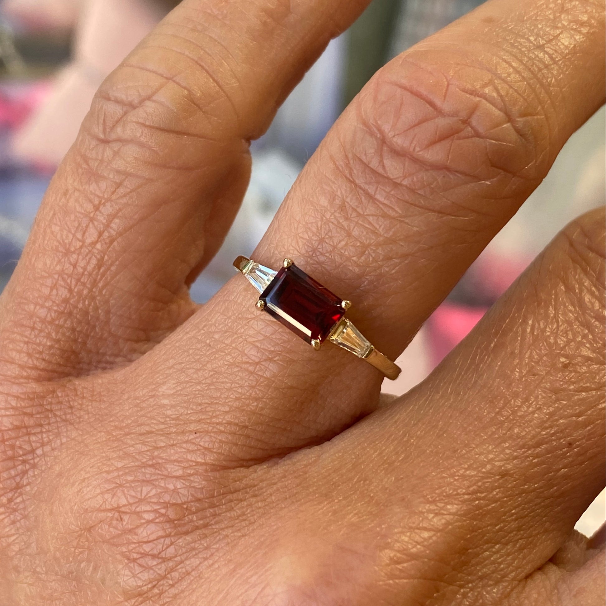 Insignia 9ct gold east-west ring featuring a garnet center stone with CZ accents on a white background.