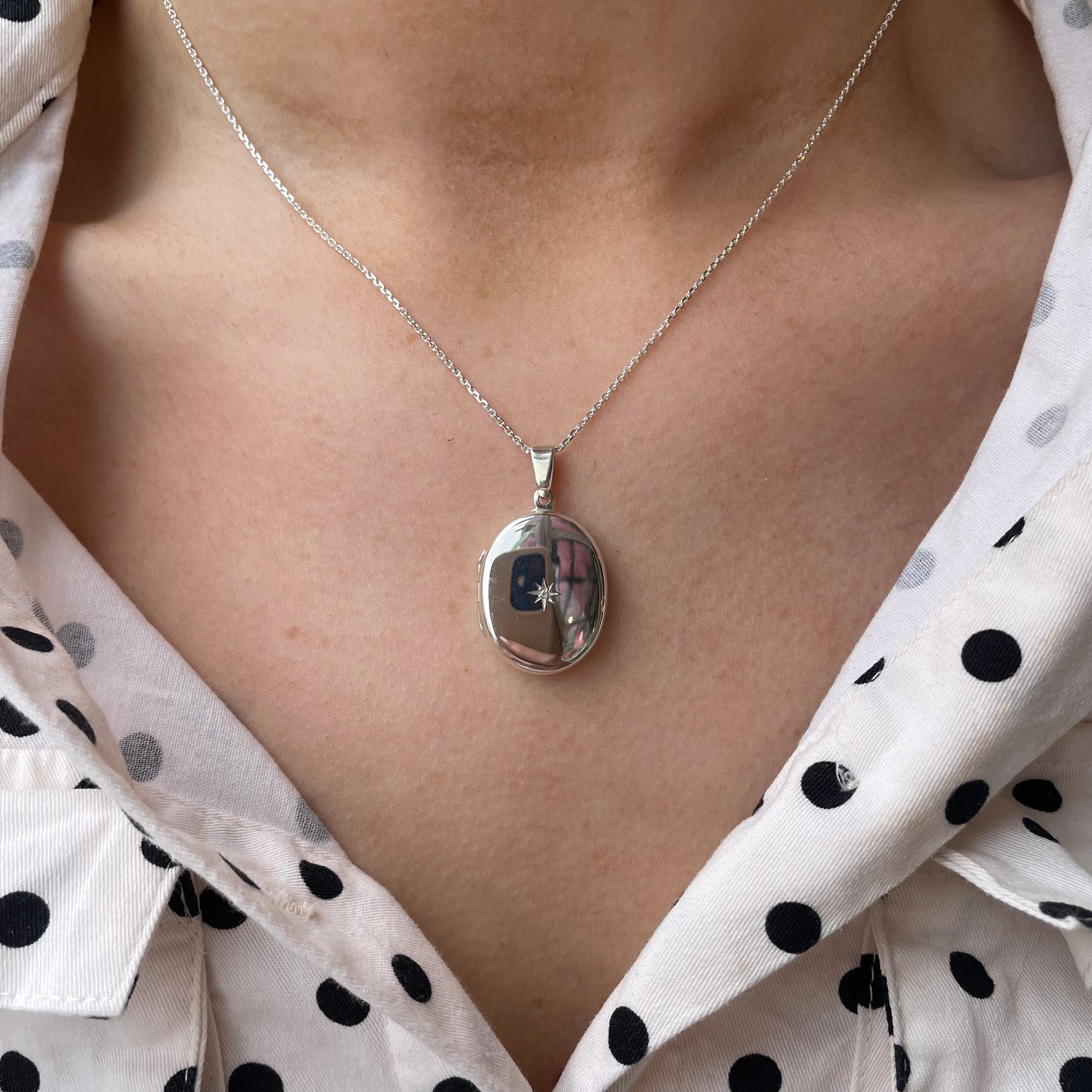 Silver diamond set oval locket necklace by Clandela featuring a polished oval pendant with sparkling diamond accents.