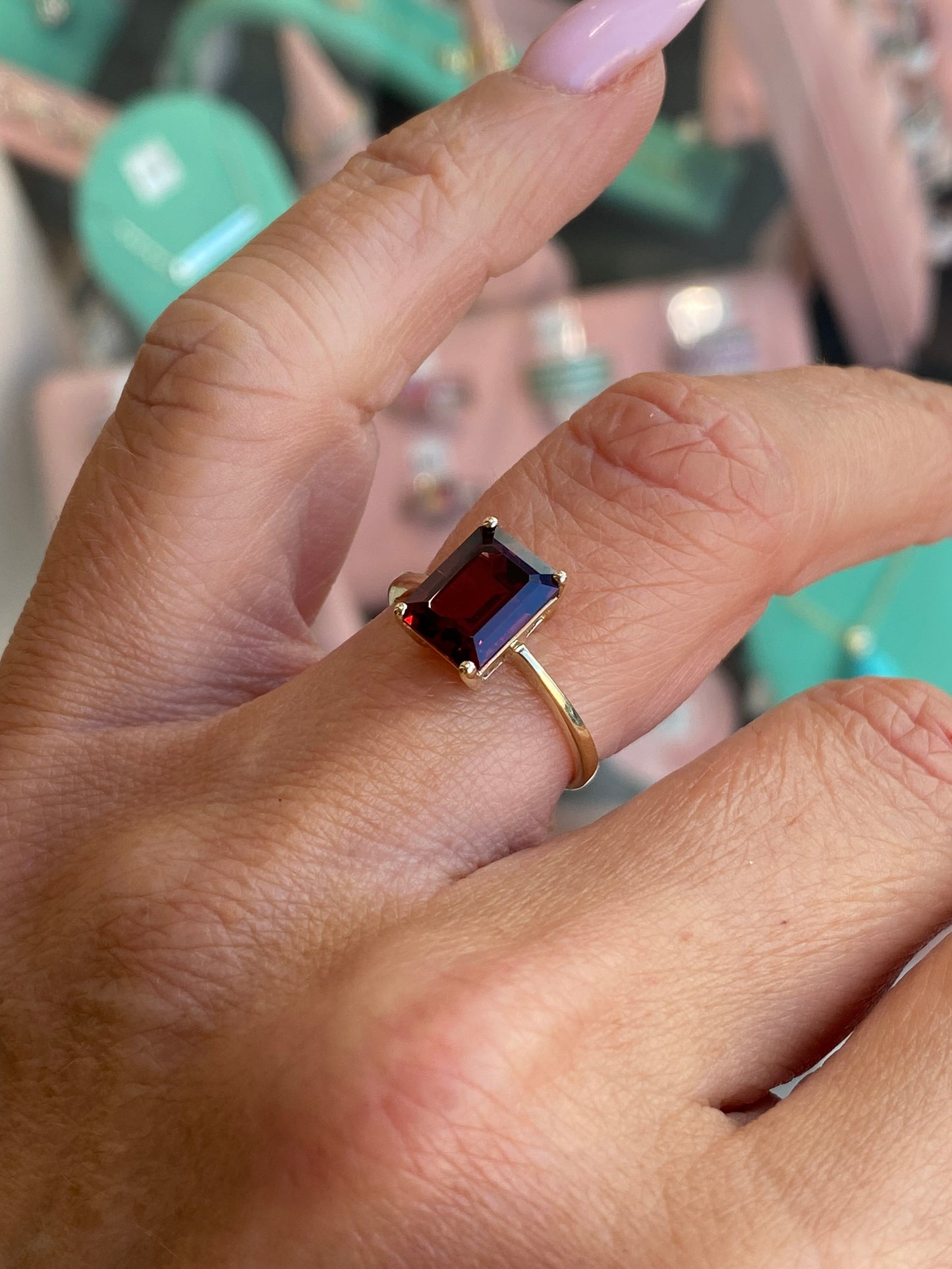 Insignia 9ct gold emerald cut garnet ring with a sleek band and polished finish, showcasing a vibrant red gemstone.