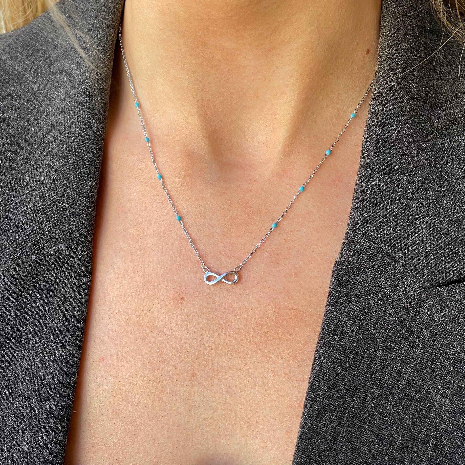 Silver synthetic turquoise infinity necklace by Comero, featuring a delicate design and adjustable chain length of 42+3cm.