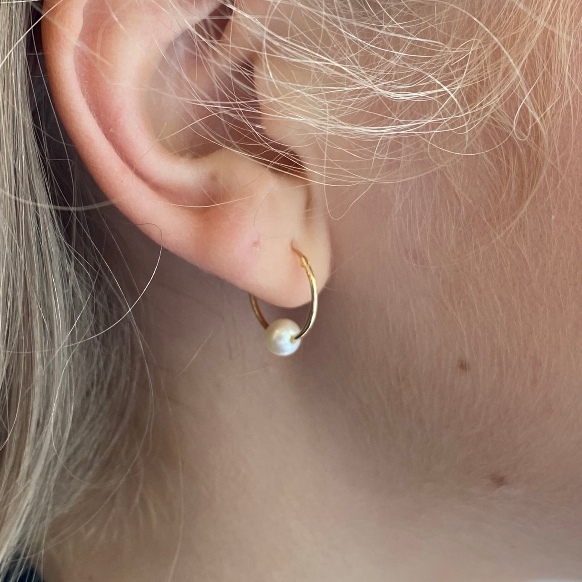 9ct gold sleeper earrings with pearl slider from THC, showcasing elegant gold hoops with hanging pearl accents.