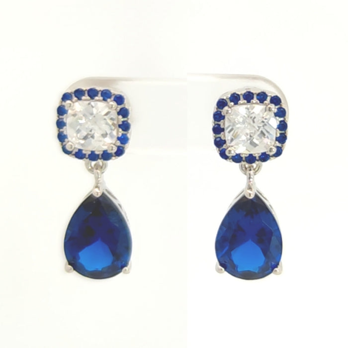 Silver sapphire blue pear-shaped CZ drop earrings by Comero featuring elegant dangle design and sparkling gemstone accents.