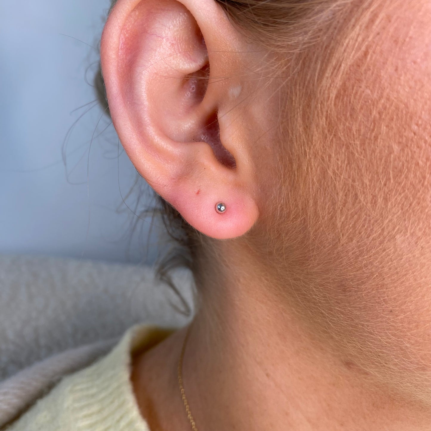 Silver nano ball stud earrings for kids by Comero, close-up of small, shiny jewelry with smooth round ball design.