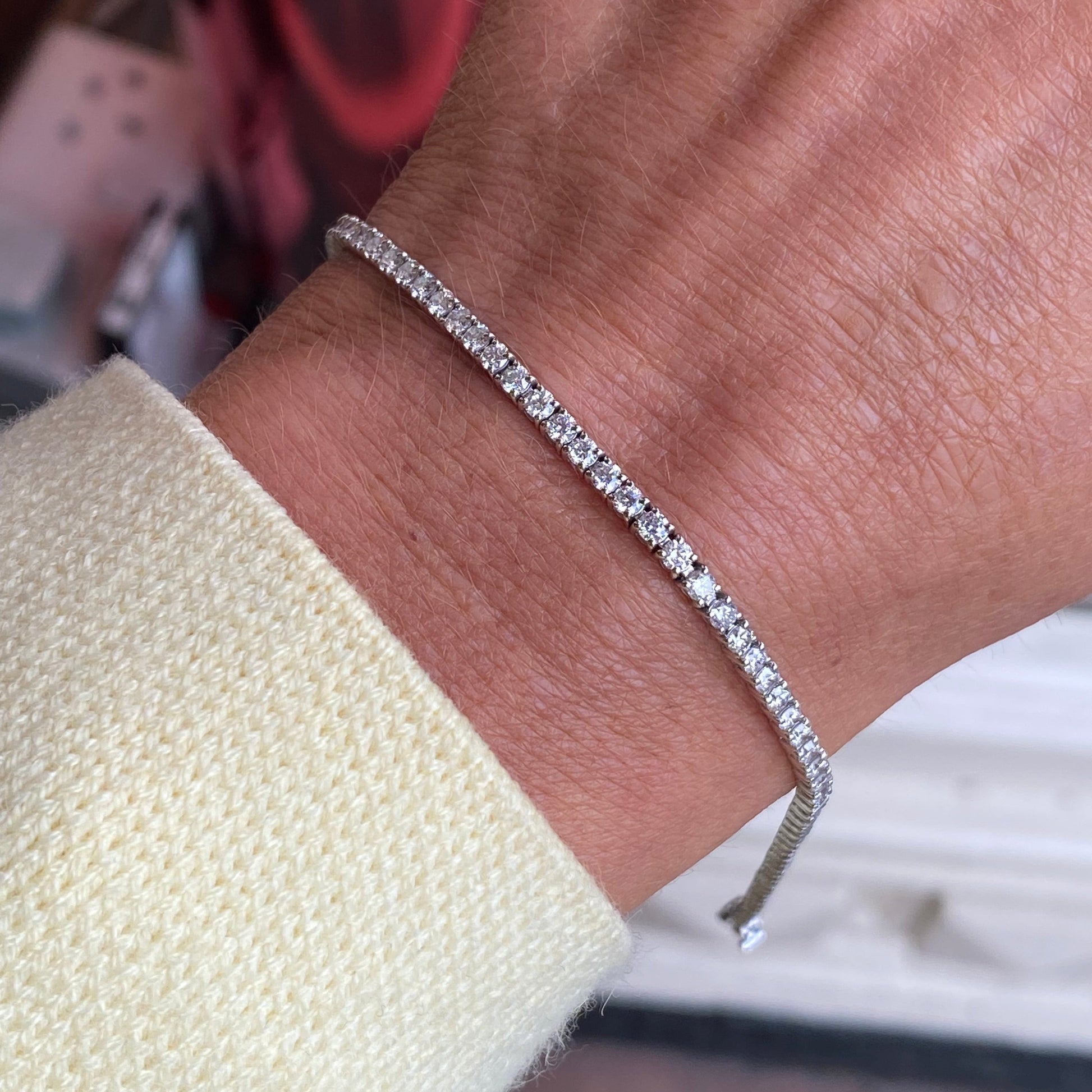 Platinum bracelet set with 3.00ct of round brilliant cut natural diamonds on a wrist with a blurred background