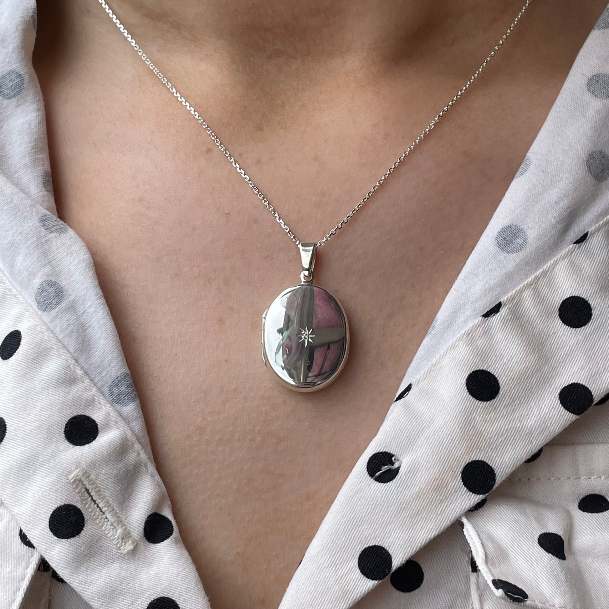 Silver diamond-set oval locket necklace by Clandela featuring a polished silver finish and intricate oval design.