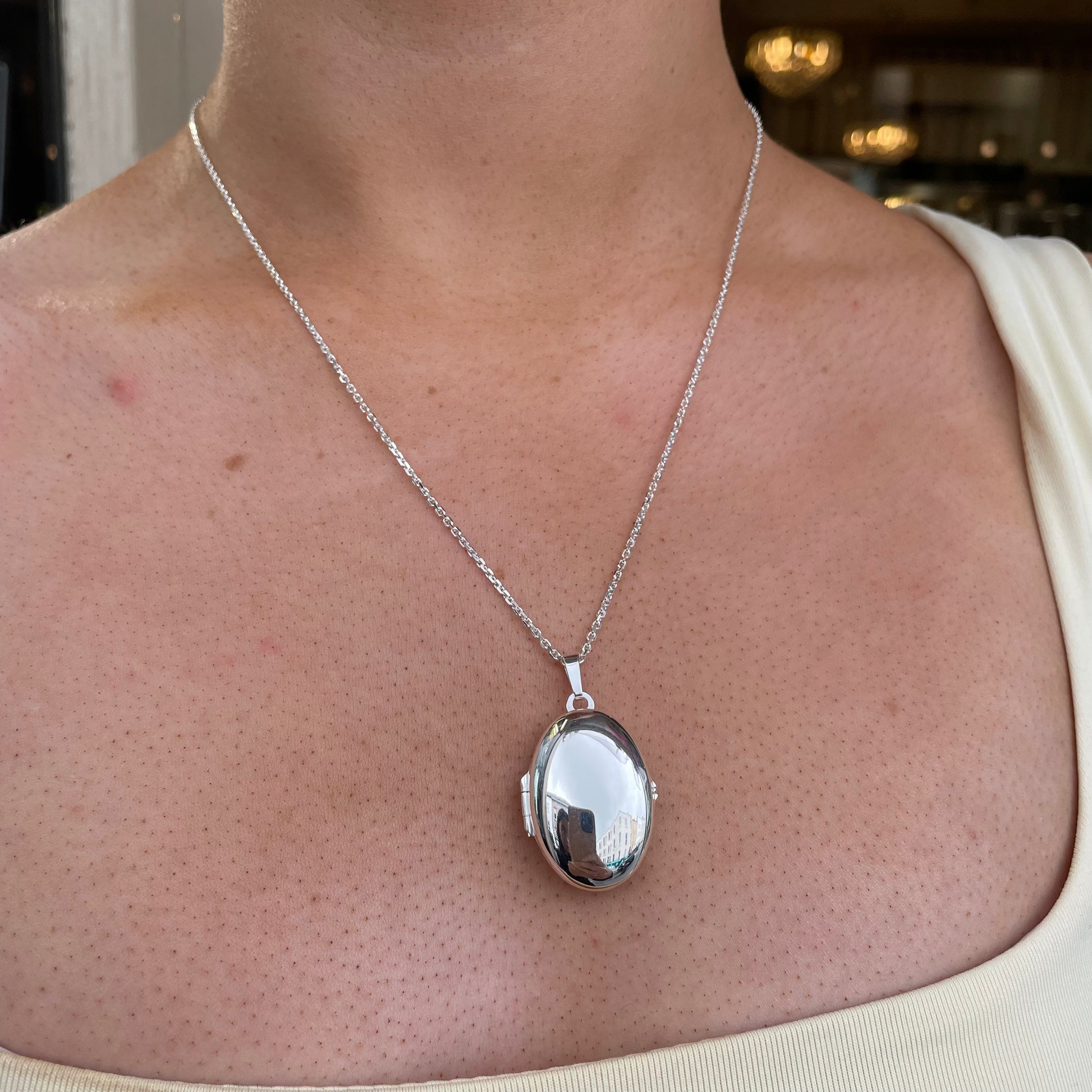 Silver Secret Heart Oval Locket Necklace by Clandela featuring a heart-shaped oval pendant on a delicate chain.