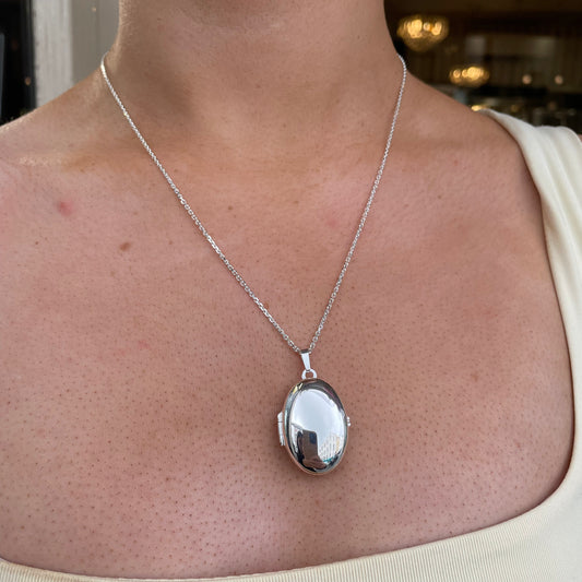 Silver Secret Heart Oval Locket Necklace by Clandela featuring a heart-shaped oval pendant on a delicate chain.