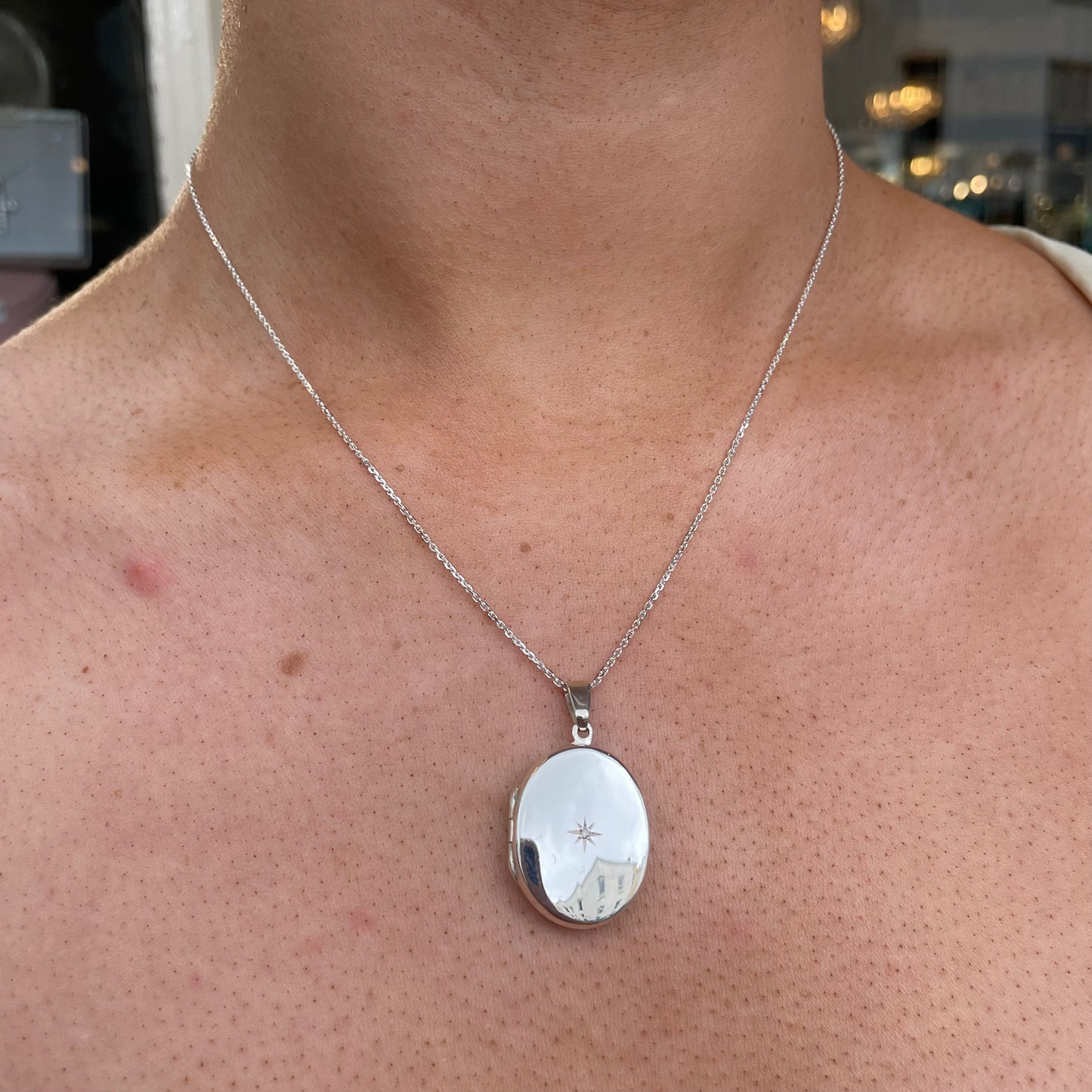 Silver diamond-set oval locket necklace by Clandela, featuring a polished silver finish and intricate engraved details.