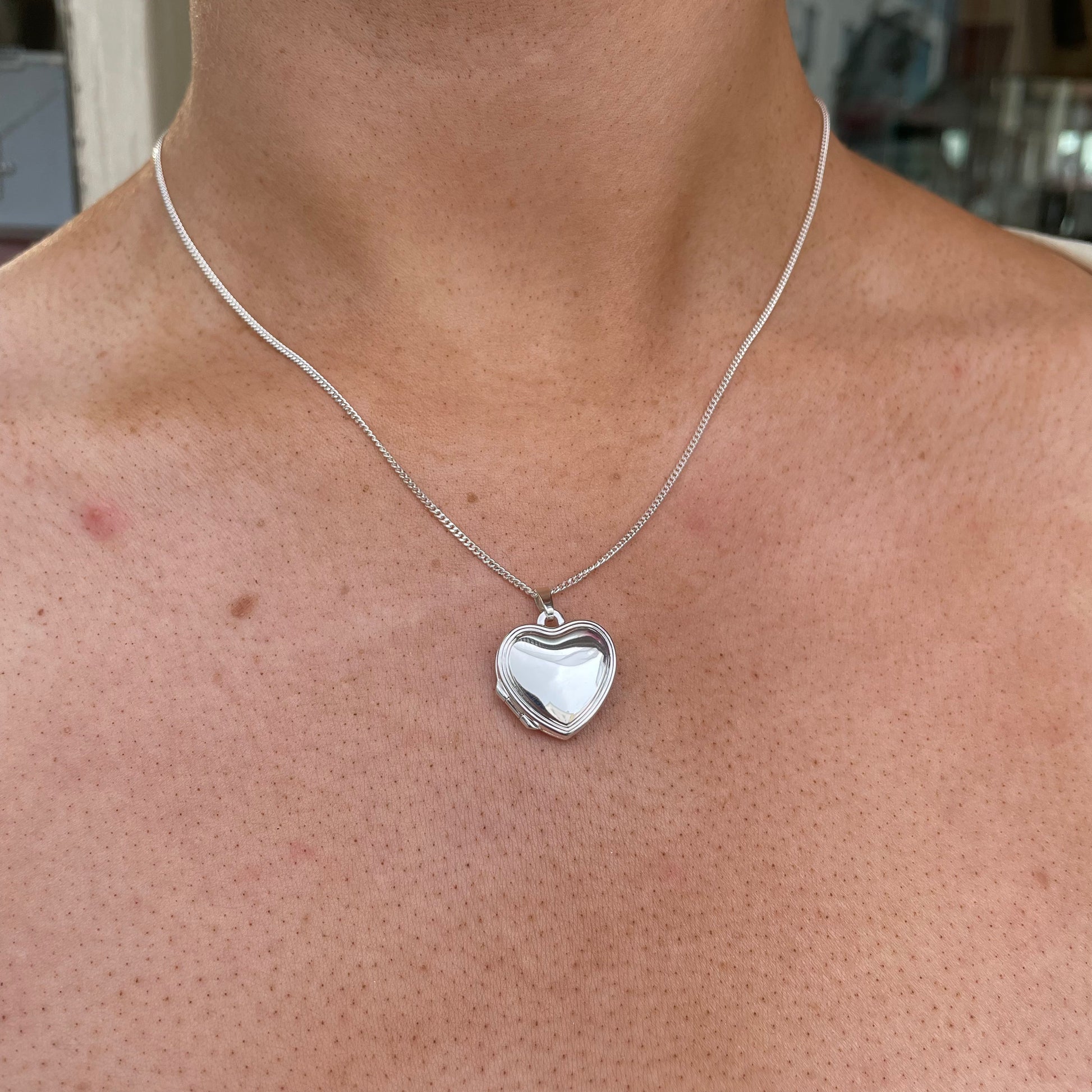 Silver stepped border heart locket necklace by Clandela, featuring a detailed heart-shaped pendant with a polished silver finish.