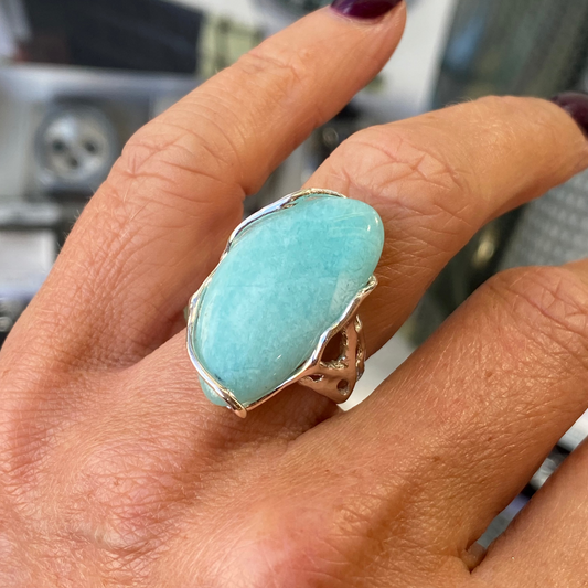 Hand wearing a large Amazonite ring with a blurred background