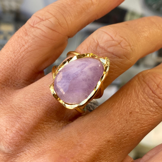 Gold ring with a amethyst stone on a person's finger