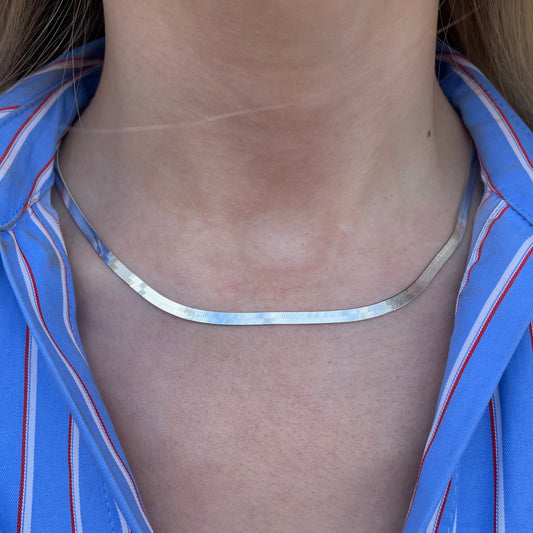 Silver necklace on a person wearing a blue striped shirt