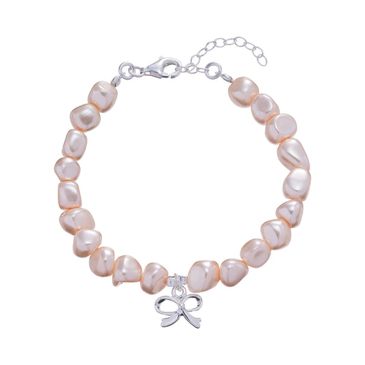 Kurate kids peachy pink freshwater pearl bracelet with bow charm, featuring a delicate and colorful jewelry accessory for children.