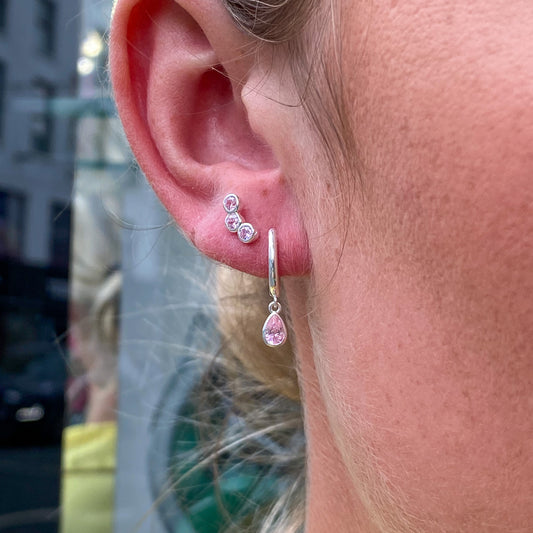 Silver pink CZ horseshoe huggie hoop earrings by CME, close-up of shiny hoops with pink cubic zirconia accents.
