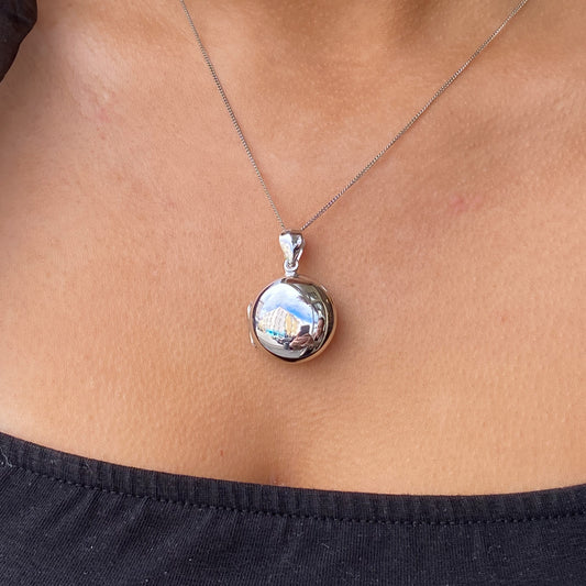 Silver polished round locket necklace with chain, featuring a shiny, smooth surface and classic design.