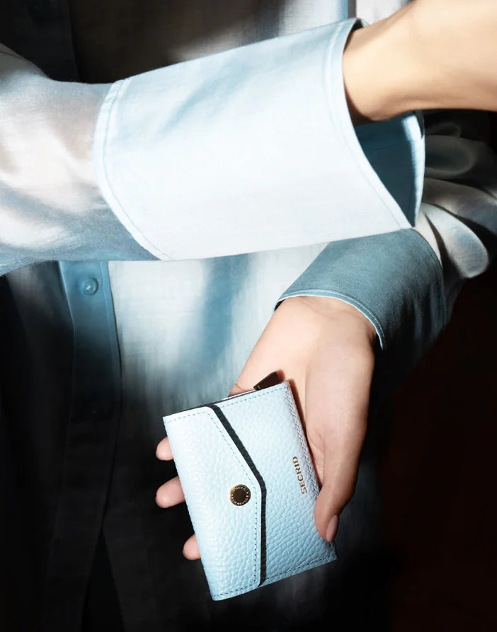 Secrid Envelope Wallet Pebble Ice Blue with textured pebble finish, compact design, and card slots, shown in a lifestyle setting.